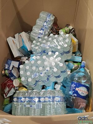 une boîte en carton remplie de bouteilles d'eau et d'autres objets