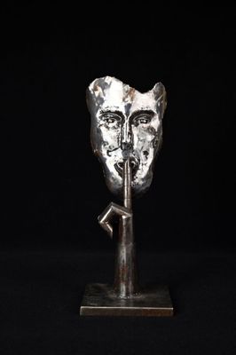 une sculpture en argent représentant une tête de chat, posée sur un socle métallique