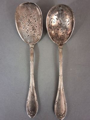 une paire de cuillères en argent ornées de motifs floraux, posées sur une table
