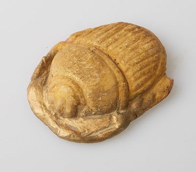 une image représentant une statue dorée d'un escargot posée sur une surface blanche