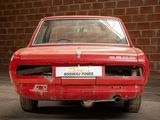 a red car that is parked in front of a brick wall