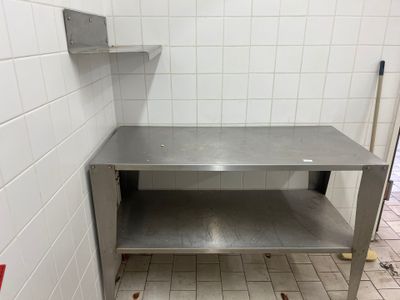 une table en acier inoxydable avec une étagère au milieu de la pièce