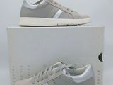 une paire de baskets grises à semelles blanches posée sur une boîte