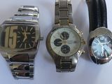 three watches are sitting next to each other on a white surface