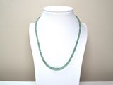 necklace made of green glass beads on a white mannequin