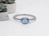 a close up of a ring with a blue topaz stone surrounded by small plants