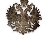 an old metal badge with a crown and two birds on it