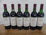 six bouteilles de vin rouge sont alignées sur une table en bois