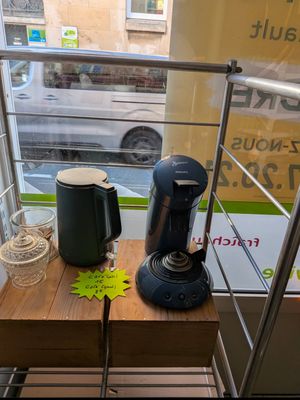 a coffee maker on a wooden table in front of a window
