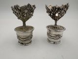 pair of silverplated vases with flowers and leaves in them
