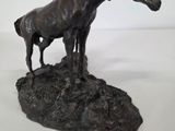 bronze statue of a horse and a foal on a rock
