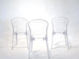three clear chairs sitting next to each other on a white surface