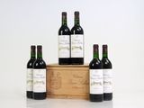 four bottles of red wine in a wooden box on a white surface