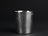 a silver cup on a black surface with a black background