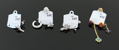 quatre breloques différentes, accompagnées de leurs étiquettes de prix, posées sur une surface noire