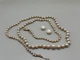 un gros plan d'un collier et de boucles d'oreilles en perles blanches posés sur une surface blanche