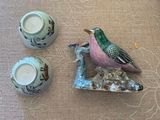 un petit oiseau perché sur une assiette, à côté de deux tasses