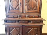 Une vieille armoire en bois trône sur un sol à carreaux noirs et blancs.