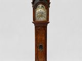 une grande horloge de parquet en bois, surmontée d'un pendule