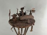 sculpture of a group of people riding on top of a wooden table