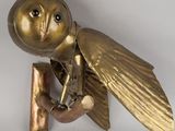 a gold owl sculpture on a wall mounted on a white wall