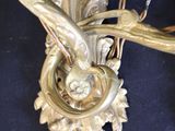 a gold wall sconce with a bird and flowers on it