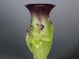 a green vase with a bird on it on a gray surface