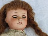 a close up of a doll with long red hair