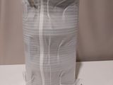 a white vase on a white table with a white curtain