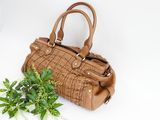 brown leather handbag on white background with green plant