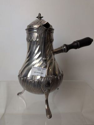 a silver coffee pot with a handle on a glass table