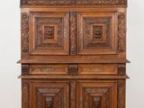 une vieille armoire en bois ornée de sculptures sur le dessus, posée sur un parquet en bois massif