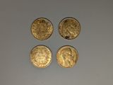 quatre types différents de pièces d'or reposant sur une surface blanche