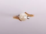 gros plan d'une bague en perles et diamants sur une surface blanche