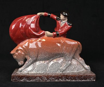 figurine of a woman sitting on top of a red bear