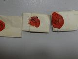 three pieces of paper with red wax on them sitting next to each other