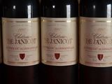 four bottles of red wine are lined up on a table
