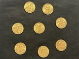 six pièces d'or sont disposées en cercle sur une surface noire