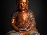 a statue of a buddha sitting on a rock with a black background