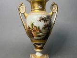 a vase with a painting on it on a stand