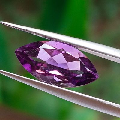 an image of a purple gemstone being held by a pair of tweezers