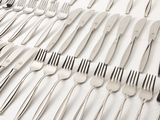 a lot of forks and spoons laid out on a table
