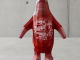a red penguin that is standing in front of a concrete wall
