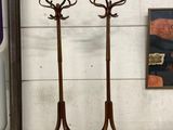 two wooden coat stands with hooks on them in front of a wall