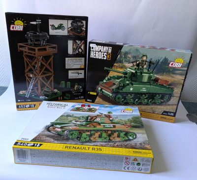 trois boîtes de véhicules militaires lego posées sur une table