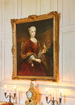 un tableau représentant une femme en robe rouge et une horloge posée sur une table