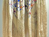 a white shawl hanging on a wall next to a white wall