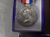 medal in a purple box with a red, white, and blue ribbon around it