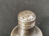 a silver pepper shaker on a plate on a table