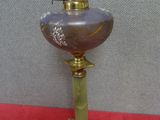 une lampe ancienne en laiton et en verre violet posée sur une nappe rouge